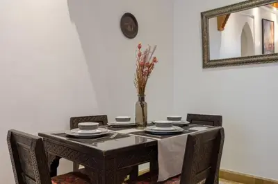 a table with chairs and a vase of flowers on it at Appartement de luxe à Palmeraie Village 2 in Marrakech