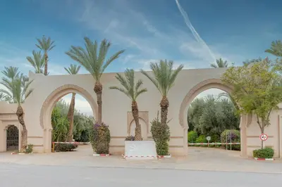 a building with palm trees in front of it at Appartement de luxe à Palmeraie Village 2 in Marrakech