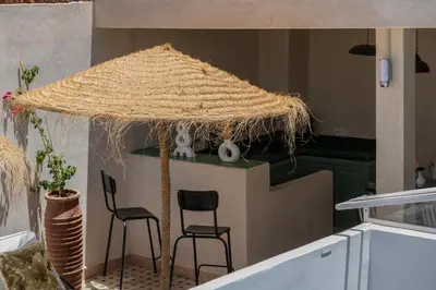 a large straw umbrella in a kitchen with two chairs at Riad Kasbah El Mamoune in Marrakech