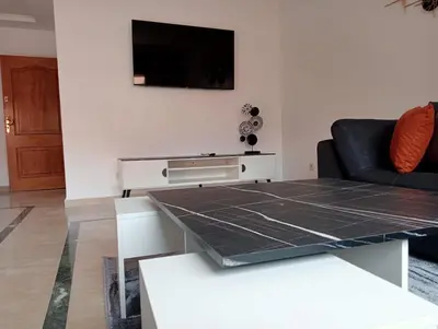 a living room with a table and a tv on a wall at Lovely Marrakech in Marrakech