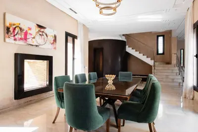 a dining room with a table and green chairs at Villa les Palmiers in Marrakech