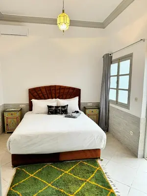a bedroom with a large bed with a green rug at Riad Arrahma in Marrakech