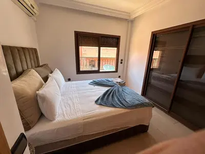 a bedroom with a bed with a window and a window at APPARTEMENT JAWHARA HIVERNAGE in Marrakech