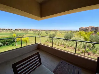 a balcony with a bench and a view of a field at Marrakech Prestigia Golf City - beauty Appartement in Marrakech