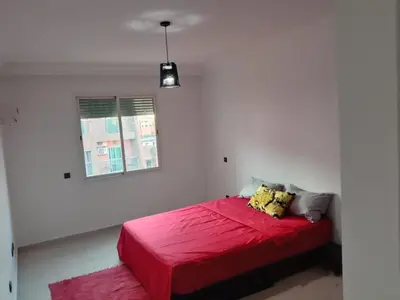 a red bed in a white room with a window at Nic's apartment in Marrakech
