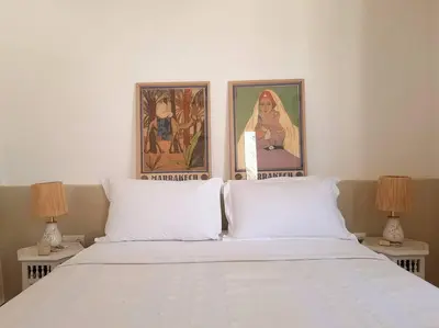 a bedroom with a bed with two lamps and two paintings at Riad Nour, Maison de charme. in Marrakech