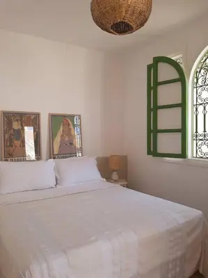 a bedroom with a white bed and a green window at Riad Nour, Maison de charme. in Marrakech