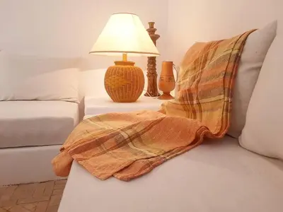 a blanket sitting on a couch next to a lamp at Riad Nour, Maison de charme. in Marrakech