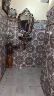 a bathroom with a mirror and a tiled wall at WOLFY’s Apartment in Marrakech