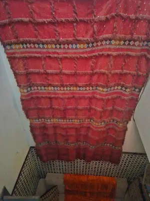 a red rug is hanging on a wall at kech hostel in Marrakech