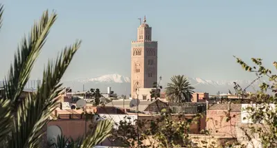 a clock tower in a city with mountains in the background at Palais Riad Lamrani in Marrakech