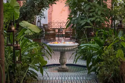 a fountain in the middle of a garden with plants at Palais Riad Lamrani in Marrakech