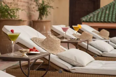 a row of wicker chairs and tables with drinks at Palais Riad Lamrani in Marrakech