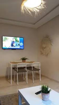 a living room with a table and a tv on the wall at Appartement gueliz 2 chambres in Marrakech