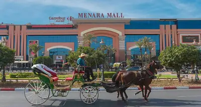 a man riding a horse drawn carriage in front of a mall at Grand Cozy Apartment in Heart of Hivernage in Marrakech