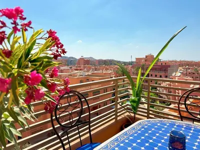 a table and chairs on a balcony with flowers at Appart Majorelle terrasse wifi centre ville in Marrakech