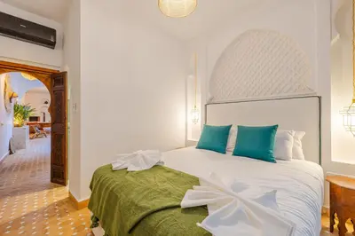 a bedroom with a large white bed with blue pillows at Riad Dar Lalla Saadia-Exclusiv-HeatedPool-Breakfast in Marrakech