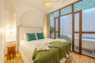 a bedroom with a bed and a large window at Riad Dar Lalla Saadia-Exclusiv-HeatedPool-Breakfast in Marrakech