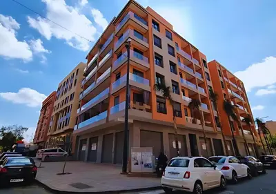 a tall building with cars parked in a parking lot at Appartement 2 ch in Marrakech