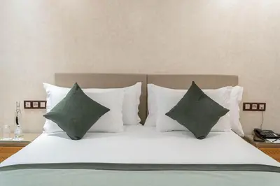 a bed with white pillows and green pillows at Riad Atlas Palace & SPA in Marrakech