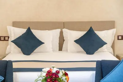 a bed with pillows and a bouquet of flowers on it at Riad Atlas Palace & SPA in Marrakech