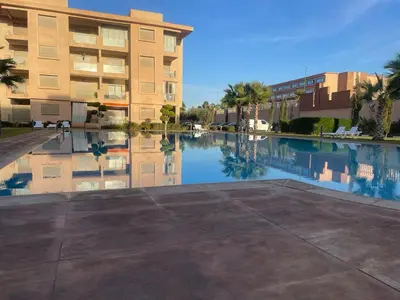 a reflection of a building in a pool of water at Appartement Coralia in Marrakech