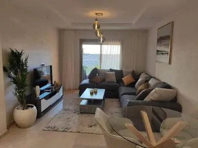 a living room with a couch and a tv at Appartement Coralia in Marrakech