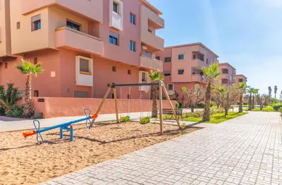 a playground in the sand in front of a building at Les Palmier de targa, Romantic appartement in Marrakech