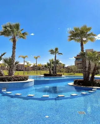a swimming pool with palm trees in a resort at Appartement Prestigia Golf City Marrakech in Marrakech