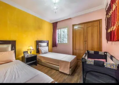 a bedroom with two beds and a yellow wall at MAJORELLE APPARTEMENT FAMILIAL in Marrakech