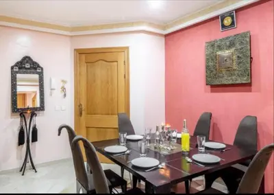 a dining room with a table and a red wall at MAJORELLE APPARTEMENT FAMILIAL in Marrakech