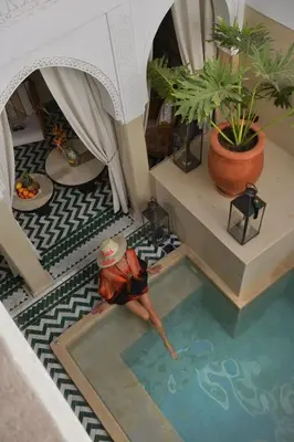 a man laying in a swimming pool in a building at Riad Palau Marrakech in Marrakech