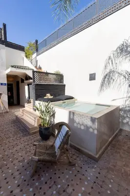a pool on a patio with a bench and a table at Riad Dar Belhaj in Marrakech