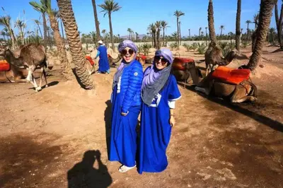 two women standing in front of a group of camels at Majestic Splendor - Marrakech Centre in Marrakech