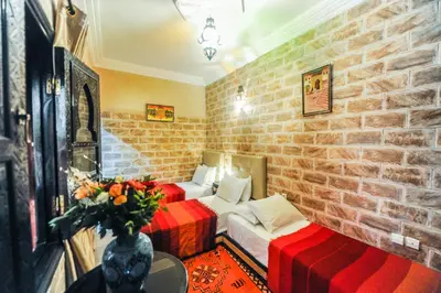 a bedroom with two beds and a brick wall at Riad Errabii & Spa in Marrakech