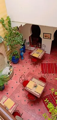 a room with tables and chairs on a red tile floor at Riad Aquarelle By GE in Marrakech