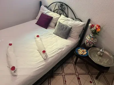 a bed with white sheets and pillows on it at HOTEL EL AMAL in Marrakech