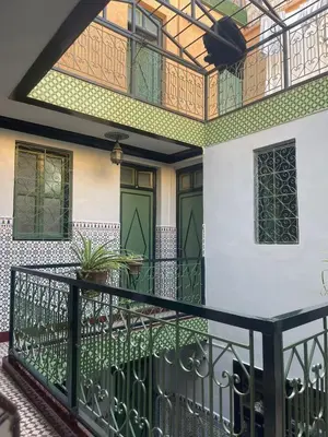 a house with a balcony with green doors at HOTEL EL AMAL in Marrakech
