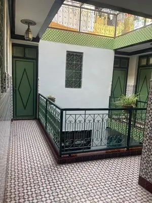 a balcony with green doors and a tiled floor at HOTEL EL AMAL in Marrakech