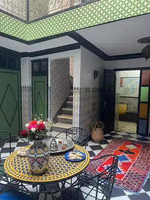 a room with a table with a vase of flowers at HOTEL EL AMAL in Marrakech