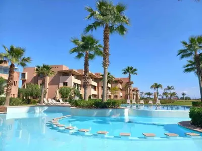 a large swimming pool with palm trees in a resort at Opale CITY GOLF Luxe Apart 3 Rooms in Marrakech
