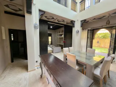a dining room with a wooden table and chairs at Sublime Villa Riad en ville avec piscine in Marrakech