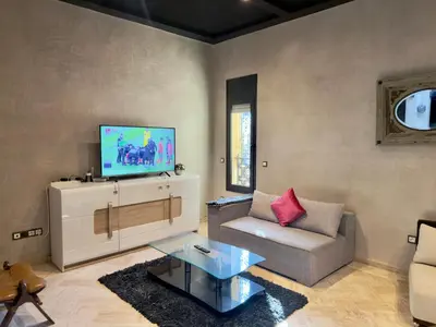 a living room with a couch and a flat screen tv at Sublime Villa Riad en ville avec piscine in Marrakech