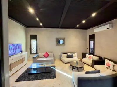 a living room with couches and a flat screen tv at Sublime Villa Riad en ville avec piscine in Marrakech