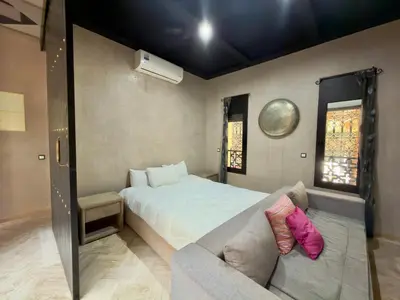 a bedroom with a large bed and a couch at Sublime Villa Riad en ville avec piscine in Marrakech
