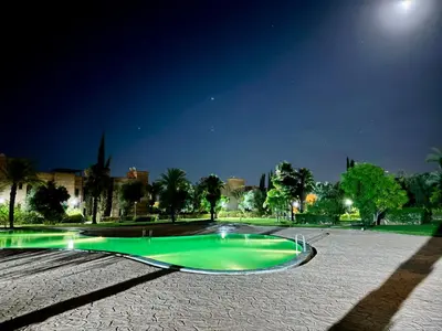 a green swimming pool in a park at night at Sublime Villa Riad en ville avec piscine in Marrakech