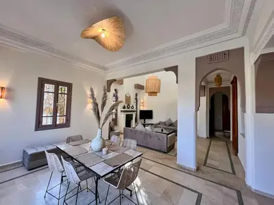 a dining room and living room with a table and chairs at Villa 1 by Majestic Properties in Marrakech
