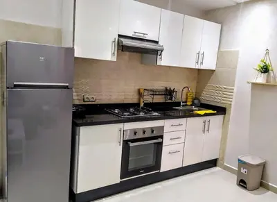 a kitchen with white cabinets and a stainless steel refrigerator at Chic & Lovely Flat in City Center in Marrakech