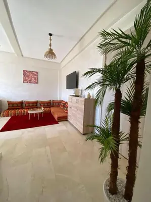 a living room with a couch and a palm tree at Appartement Marrakech luxe in Marrakech