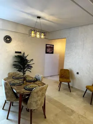 a dining room with a table and chairs with a plant on it at App centre-ville in Marrakech